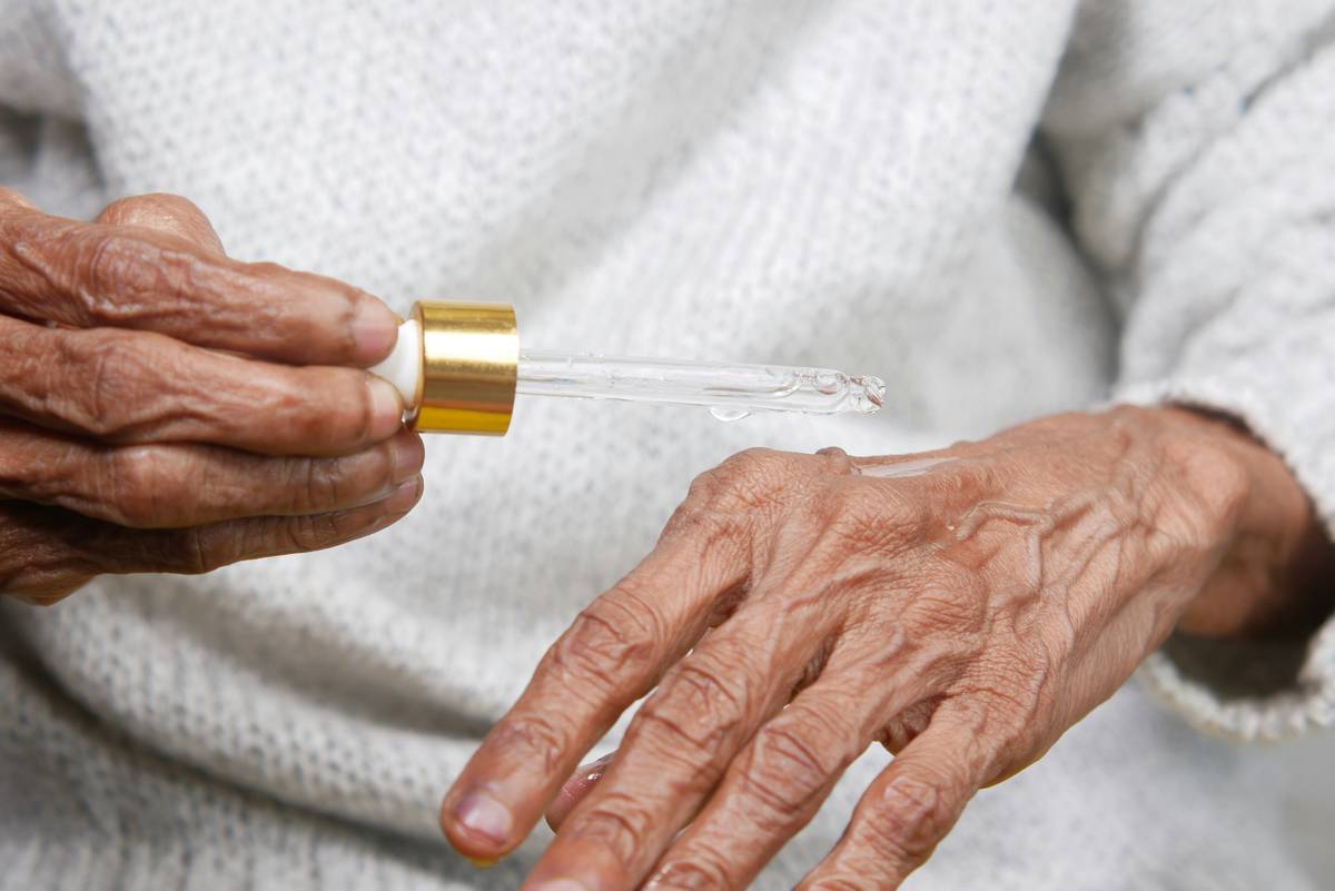 Woman applying hydrating cream butter body mature skin to arms after shower